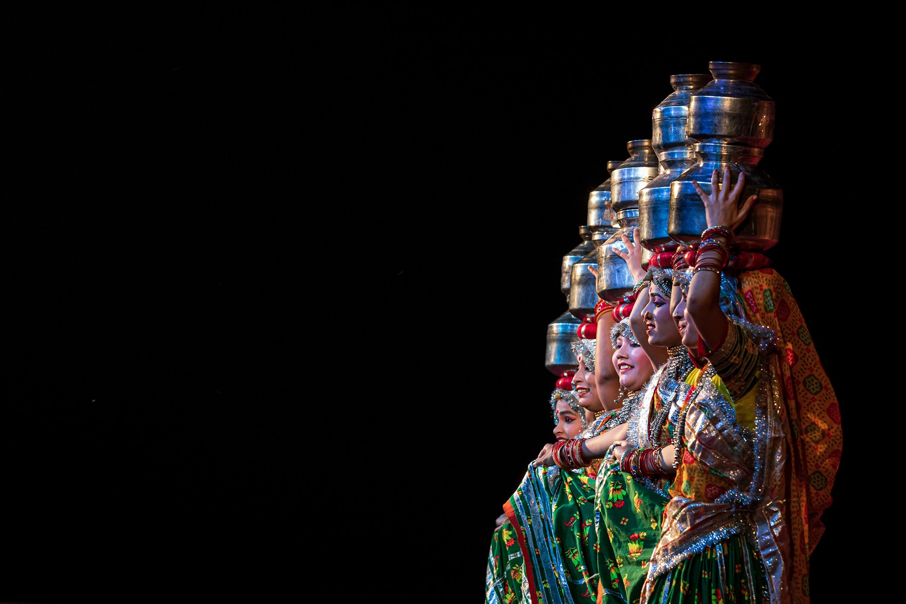 Rajasthani folk performers in vibrant traditional dress balancing polished pots during a dance performance